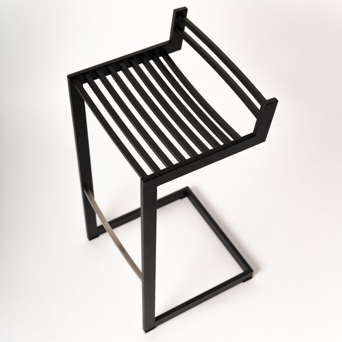 op view of Forma b Metalinea Black stool highlighting the ergonomic curved seat design and minimalist aesthetic